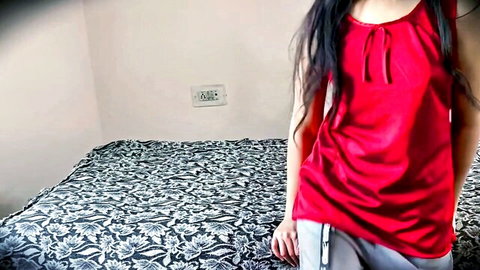 Skinny Indian girl in sexy red satin top and gray sweatpants posing in bedroom