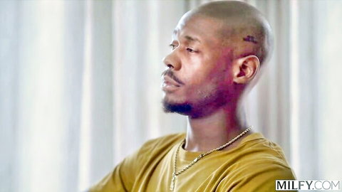 Bald black man with head tattoo and gold chain in yellow shirt close-up