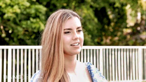 Young blonde babe with long hair smiling in floral dress outdoors