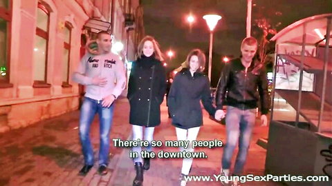 Young adults walking hand-in-hand to wild sex party orgy on neon-lit downtown street