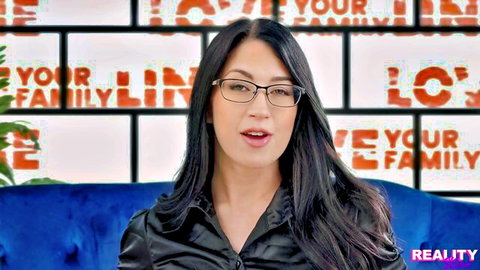 Asian brunette in glasses speaks seductively on couch with 'I love your family' taboo background