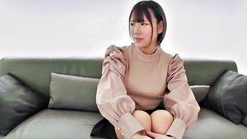 Petite Asian woman in fitted beige top and short skirt sitting seductively