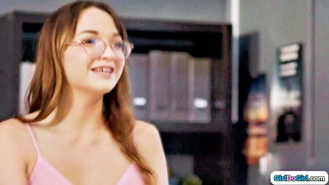 Cute brunette teen with glasses smiling in tight pink top showing cleavage in office