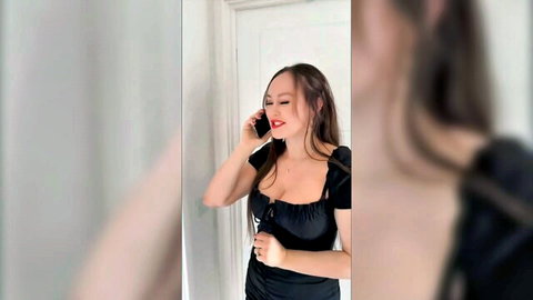 Buxom brunette in low-cut black dress on phone, teasing with big tits