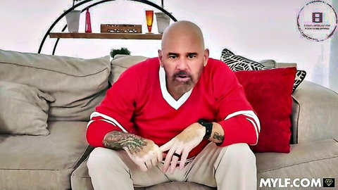 Bald Latino man in red jersey, tattooed arms, intense gaze