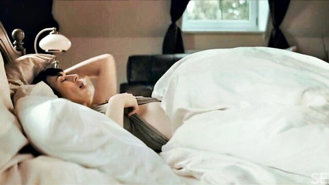 Olive Glass teasing seductively under white blanket in bed