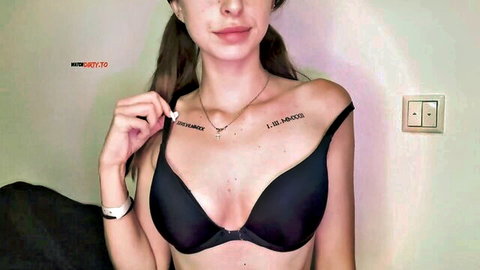 Tattooed teen babe pulls down black bra strap showing deep cleavage tits