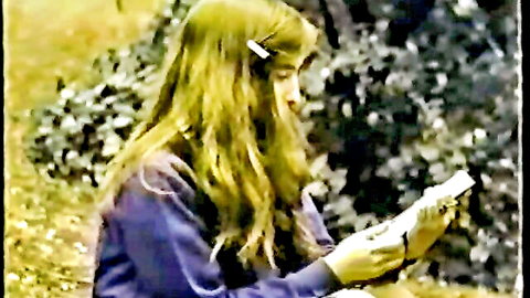 Blonde girl in purple sweater and white gloves reads book in garden, classic XXX thumbnail