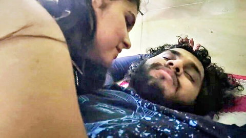 Hot Indian woman passionately kissing bearded man's face in bed