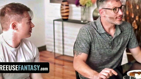 Stepdad in polo shirt smiles at stepson in white tee during tense family dinner