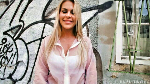 Blonde MILF smiles with big tits and hard nipples visible through sheer open blouse by graffiti wall
