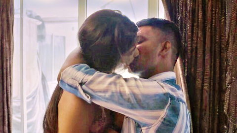 Hot Indian babe with bare tits passionately kissing muscular guy in striped shirt