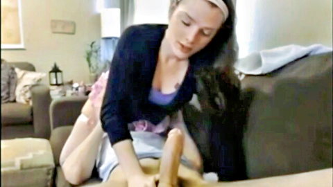 Brunette woman straddles friend on couch fucking her pussy with huge beige dildo