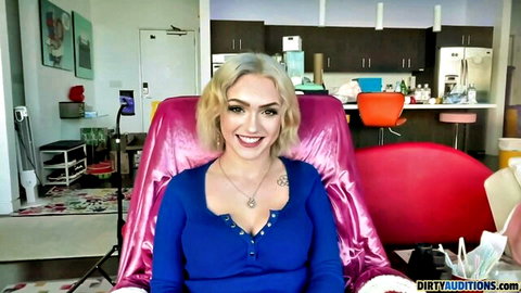 Blonde babe with tattoos smiles seductively showing cleavage in blue top on Dirty Auditions