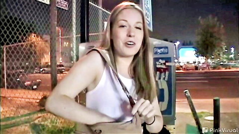 Blonde babe in tight white tank top smiling seductively by public payphone on dark street