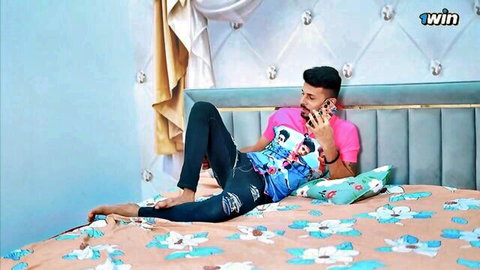 Indian man lounging on bed in casual outfit, phone call tease