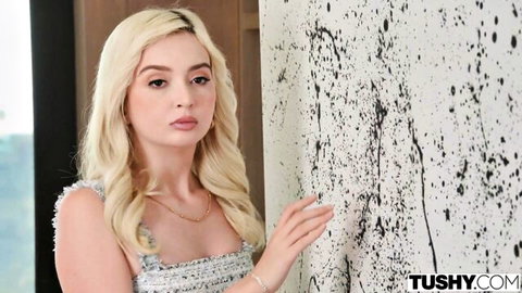Petite blonde with small tits in sexy lace dress posing teasingly against splattered wall