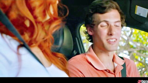 Redhead woman in white top smiles at handsome guy in polo shirt inside car