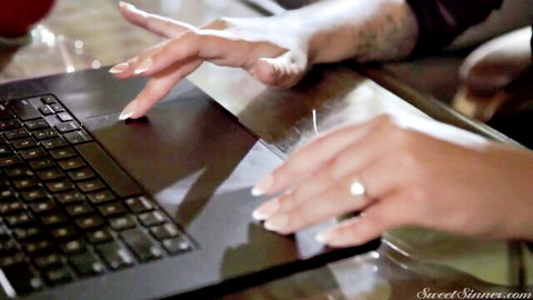 Sophia Locke with tattooed hands typing on laptop in steamy stepmom scene