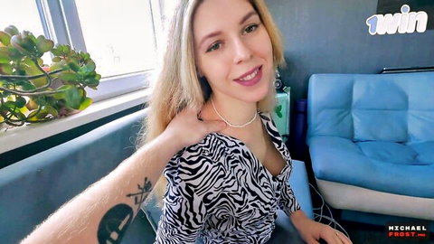 Blonde in zebra top smiles showing cleavage with tattooed boyfriend's arm around her