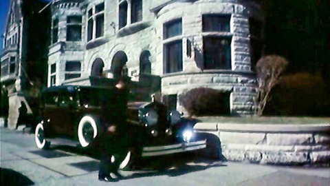 Vintage black-and-white scene of classic car outside mansion, no explicit content visible