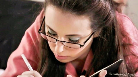 Casey Calvert in glasses and pink top, focused on tablet with pen