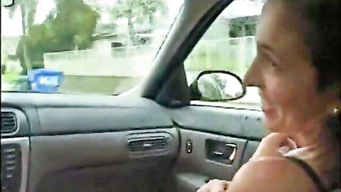 Smiling brunette woman in car passenger seat wearing tank top