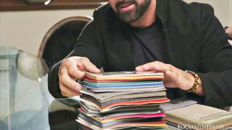 Rocco Siffredi holds colorful fabric swatches in office setting