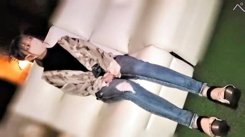 Hot Japanese babe in camo jacket and ripped jeans lounging seductively