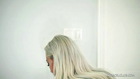 Long-haired blonde babe posing seductively in white room side profile