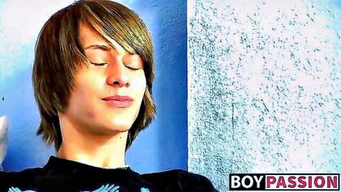 Cute shaggy-haired twink boy closes eyes smiling blissfully in black t-shirt
