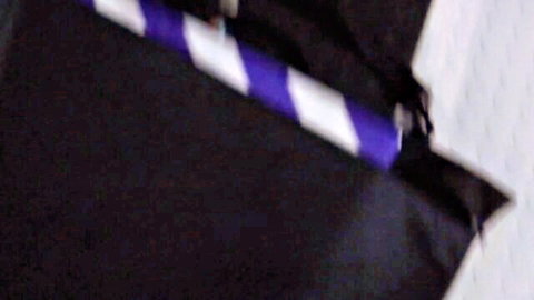 Closeup of purple and white striped stripper pole with black fabric in dark studio