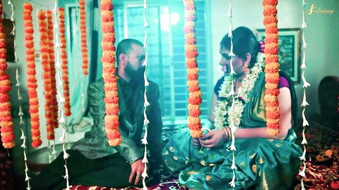 Intimate Indian couple in green saree and suit gazing passionately amid marigold garlands
