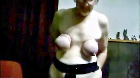Grey-haired mature woman flaunts large granny tits topless