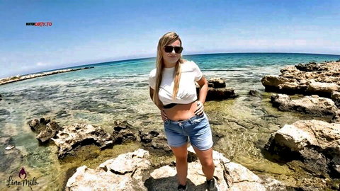 LinaMila blonde in white crop top and denim shorts on sunny beach rocks