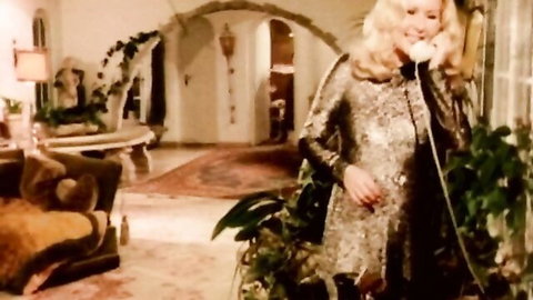 Vintage blonde in shiny metallic dress on phone call, elegant pose