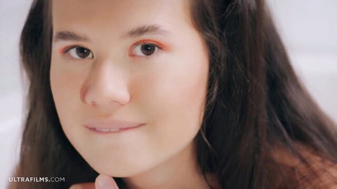 Young brunette with long hair smiling sensually in bathroom closeup