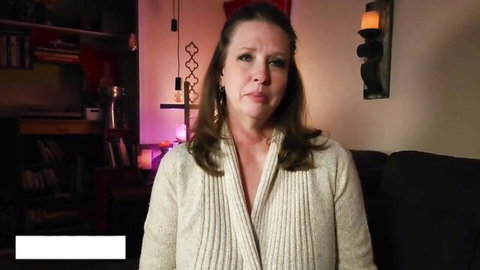 Mature brunette in open cardigan showing cleavage on couch