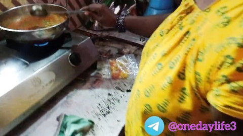 Hot Indian wife in yellow dress stirring pot in kitchen