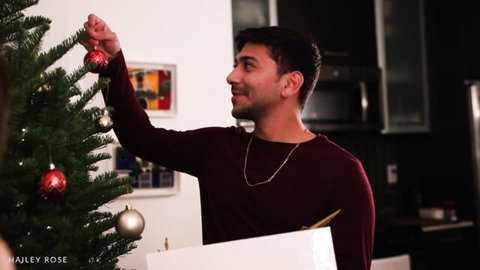 Max Crams hangs ornaments on Christmas tree in holiday setup with Hailey Rose
