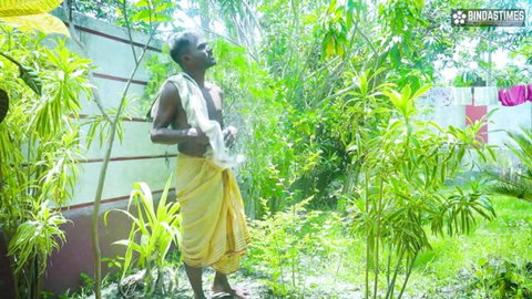 Mature Indian man in yellow dhoti standing outdoors in garden