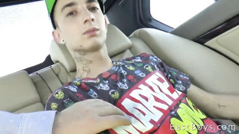 Tattooed young twink in Marvel shirt leans back in car backseat as hand gropes crotch bulge