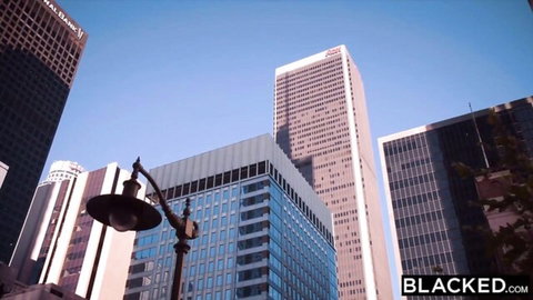 Downtown LA skyscrapers and street lamp under blue sky with BLACKED.COM watermark