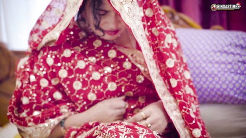 Desi bride in red embroidered lehenga, veiled and seductive pose