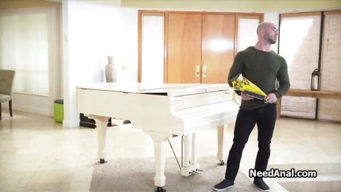 Bald man holds yellow funnel by piano in anal video teaser