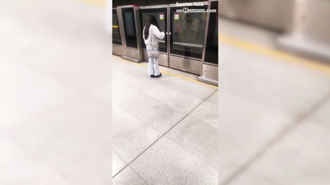 Indian girl in tight white pants stands at subway platform, teasing view