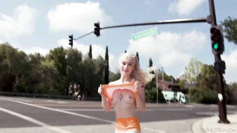 Emma Rosie lifts torn orange top, exposing perky tits outdoors at traffic light