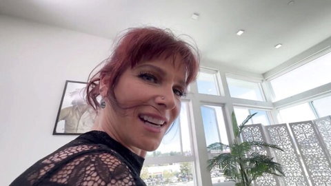Smiling redhead MILF in sheer black lace top teasing cleavage