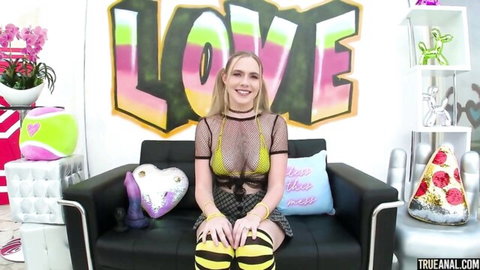 Young blonde in sheer mesh top exposing small tits and micro skirt teasing legs spread on couch