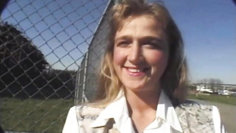 Shy blonde newbie smiling outdoors in white shirt and vest